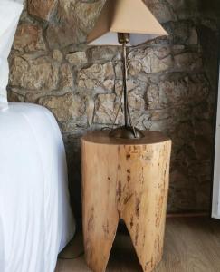 a lamp on top of a wooden stump next to a bed at O Refúgio das Buracas in Condeixa a Nova