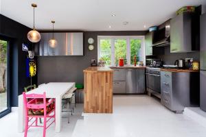 uma cozinha com uma mesa e uma cadeira rosa em Veeve - Highgate High Notes em Londres