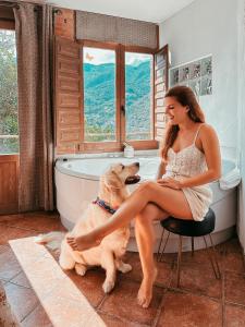 Eine Frau, die auf einem Stuhl neben einem Hund im Badezimmer sitzt. in der Unterkunft El Ablanu Senda del Oso in Proaza