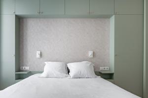 a white bed with two white pillows on it at Veeve - Back to Black in Paris