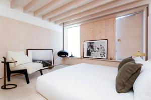 a bedroom with a white bed and a chair at Veeve - Brazilian Trailblazer in London