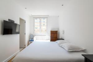 um quarto branco com uma cama grande e uma televisão em Veeve - Ethereal Light em Paris