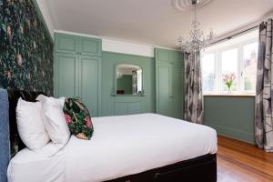 a bedroom with a bed with green walls and a chandelier at Veeve - Parkland Perfection in London