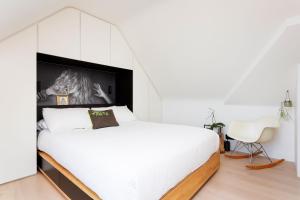 a bedroom with a white bed and a white chair at Veeve - Celestial Loft in London