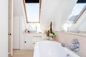 a bathroom with a bath tub and two windows at Veeve - Celestial Loft in London