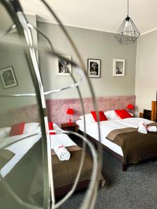 波兹南Expolis Residence - City Center - 24h #betterthanyourEX的一间卧室配有两张带红色枕头的床