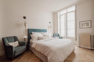 a bedroom with a large bed and a blue chair at Veeve - Poetic Harmony in Paris