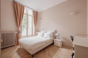 a white bedroom with a bed and a window at Veeve - Poetic Harmony in Paris