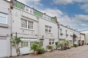 a row of white buildings with plants on a street at Veeve - Mews & Blues in London