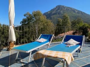 2 sillas y una mesa en un patio con una montaña en Taddore Green Lodge en Galtellì