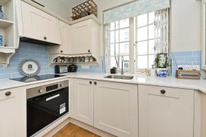 uma cozinha com armários brancos, um lavatório e uma janela em Veeve - Mews & Blues em Londres