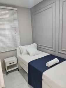 a white room with two beds and a window at Pousada Calma in Maputo