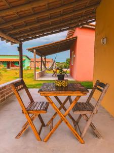 uma mesa de piquenique e duas cadeiras sob um telhado em Pousada Villa Esperança - Xandó - Caraíva BA em Caraíva