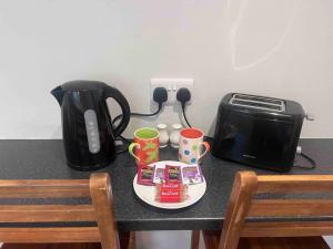 a table with a toaster and a plate with cups at Beautiful flat in city centre in Brighton & Hove