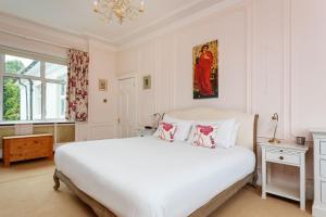 een witte slaapkamer met een groot bed en een kroonluchter bij Veeve - Courtside Dreams in Londen
