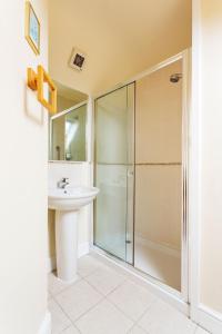 uma casa de banho com uma cabina de duche em vidro e um lavatório. em Veeve - Courtside Dreams em Londres