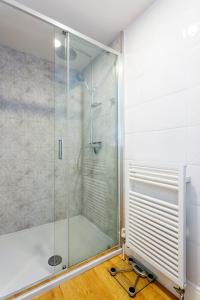 a shower with a glass door in a bathroom at Veeve - Courtside Dreams in London
