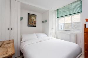 a white bedroom with a white bed and a window at Veeve - Harmonious Hideaway in London