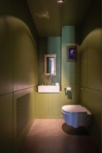 een groene badkamer met een toilet en een wastafel bij Veeve - Belle Blanche in Parijs