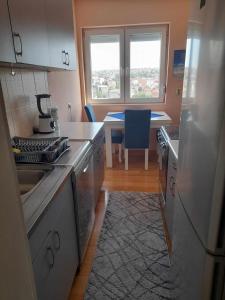 Il comprend une cuisine équipée d'un réfrigérateur et d'une table avec une fenêtre. dans l'établissement Apartman Kumanovo Centar strog, à Kumanovo