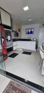 a large white kitchen with a sink and a tv at Cobertura Duplex Vista Mar in Mangaratiba