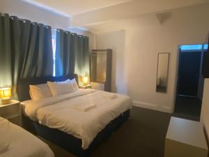 a bedroom with a bed with two lamps and a window at Abbie Lodge Guest House in Weston-super-Mare +38 photos