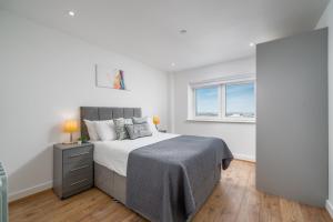 een slaapkamer met een groot bed en een raam bij Skyvillion - London River Thames Top Floor Apartments by Woolwich Ferry, Mins to London ExCel, O2 Arena , London City Airport with Parking in Londen