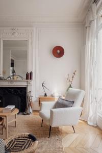 sala de estar con muebles blancos y chimenea en Veeve - Heavenly Elegance en París