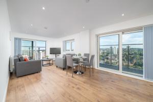 Skyvillion - London River Thames Top Floor Apartments by Woolwich Ferry, Mins to London ExCel, O2 Arena , London City Airport with Parking في لندن: غرفة معيشة مع طاولة وكراسي ونوافذ