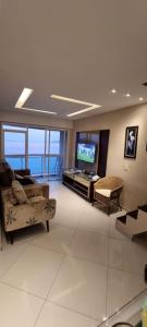 uma sala de estar com um sofá e uma televisão em Cobertura Duplex Vista Mar em Mangaratiba