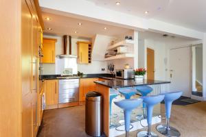 a kitchen with a bar with blue stools at Veeve - Canalside Comfort in London