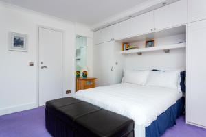 a white bedroom with a large bed with a black stool at Veeve - Canalside Comfort in London
