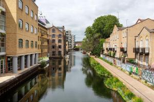 a canal in a city with buildings next to a street at Veeve - Canalside Comfort in London