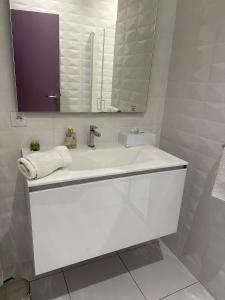 a white bathroom with a sink and a mirror at Domaine du Prieuré d'Estagel in Saint-Gilles