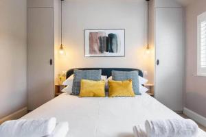 een slaapkamer met een groot wit bed met gele kussens bij The Helvellyn in Falmouth