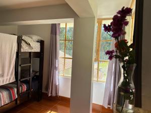 a vase with purple flowers in a room with a window at Chacraraju Lodge in Huaraz