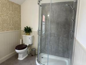 a bathroom with a toilet and a glass shower at The Victoria Hotel,Bar,Bistro in Norham