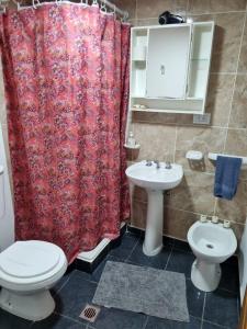 uma casa de banho com uma cortina de chuveiro vermelha e um WC e lavatório. em Cabaña Ceferino Ushuaia em Ushuaia