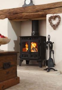 a black stove in a room with a fire at The Honeypot in Chipping Campden