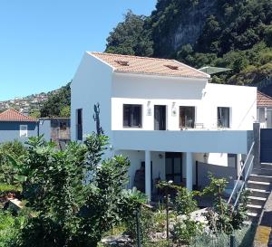 a white house with a mountain in the background at Lazy Lizard by the Ocean in Seixal