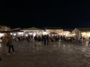 un grupo de personas de pie en una plaza por la noche en Sea House en Marzamemi