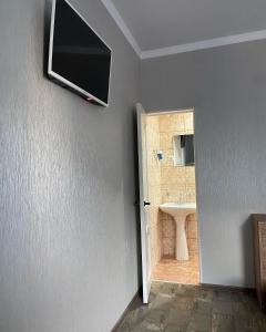a bathroom with a sink and a television on the wall at Уютный Дворик in Sukhum