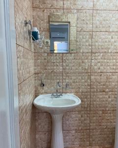a bathroom with a sink and a tiled wall at Уютный Дворик in Sukhum