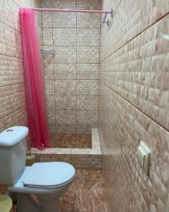 a bathroom with a toilet and a shower with a pink curtain at Уютный Дворик in Sukhum