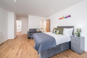 Skyvillion - London River Thames Top Floor Apartments by Woolwich Ferry, Mins to London ExCel, O2 Arena , London City Airport with Parking في لندن: غرفة نوم بسرير كبير وكرسي