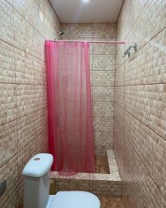 a bathroom with a shower with a toilet and a red shower curtain at Уютный Дворик in Sukhum