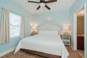a bedroom with a white bed and a ceiling fan at Laketown Wharf #119 by Nautical Properties in Panama City Beach