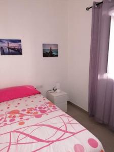 Un dormitorio blanco con una cama con una manta rosa. en Vivienda EL REMO-Vv-2, en Los Llanos de Aridane