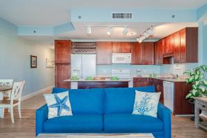 a living room with a blue couch in front of a kitchen at Laketown Wharf #119 by Nautical Properties in Panama City Beach