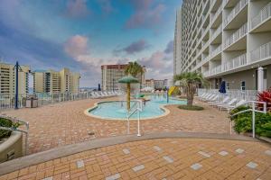a swimming pool with an umbrella and chairs and a building at Laketown Wharf #119 by Nautical Properties in Panama City Beach